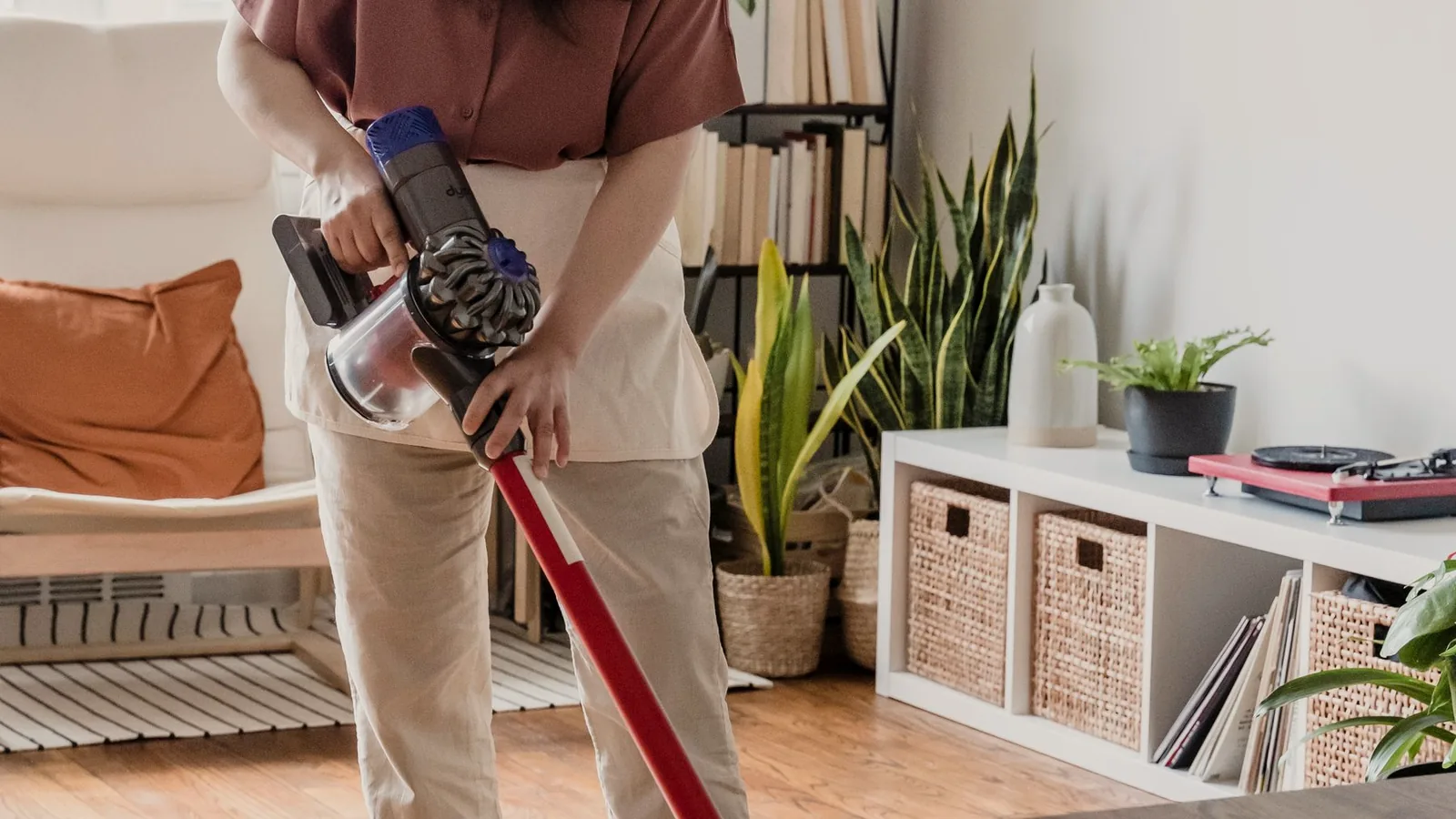 Someone vacuuming a living room floor in the middle of the day