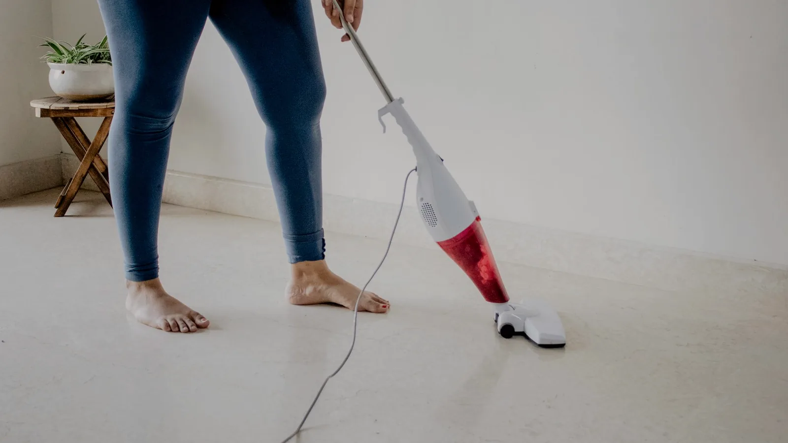 Someone vacuuming a pale floor in daylight