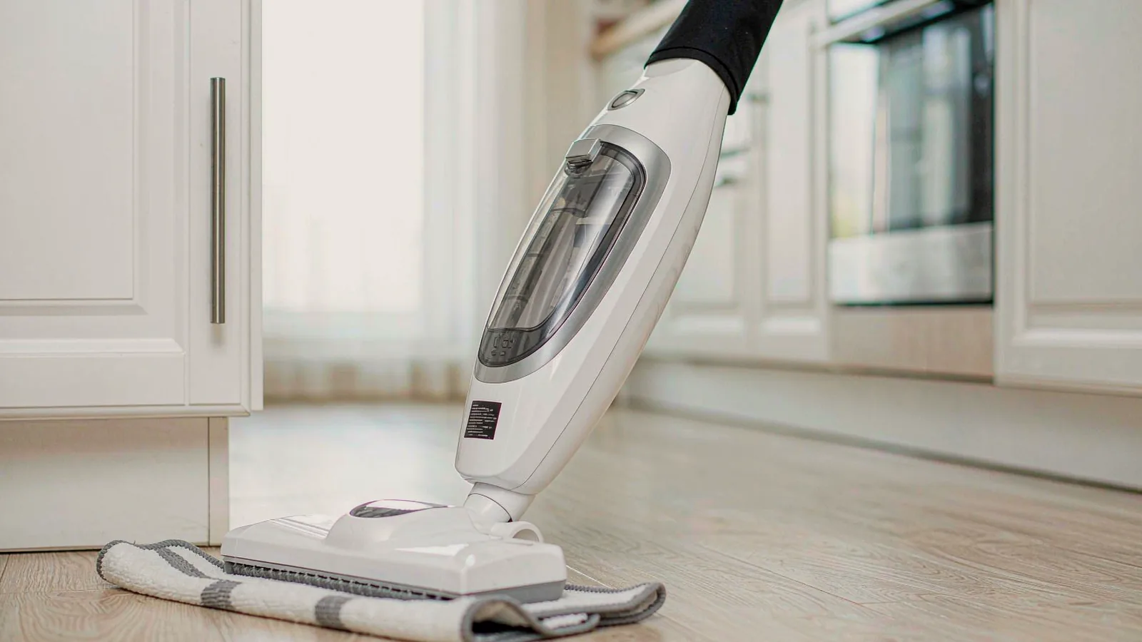 A steam mop and cloths on a light wooden floor