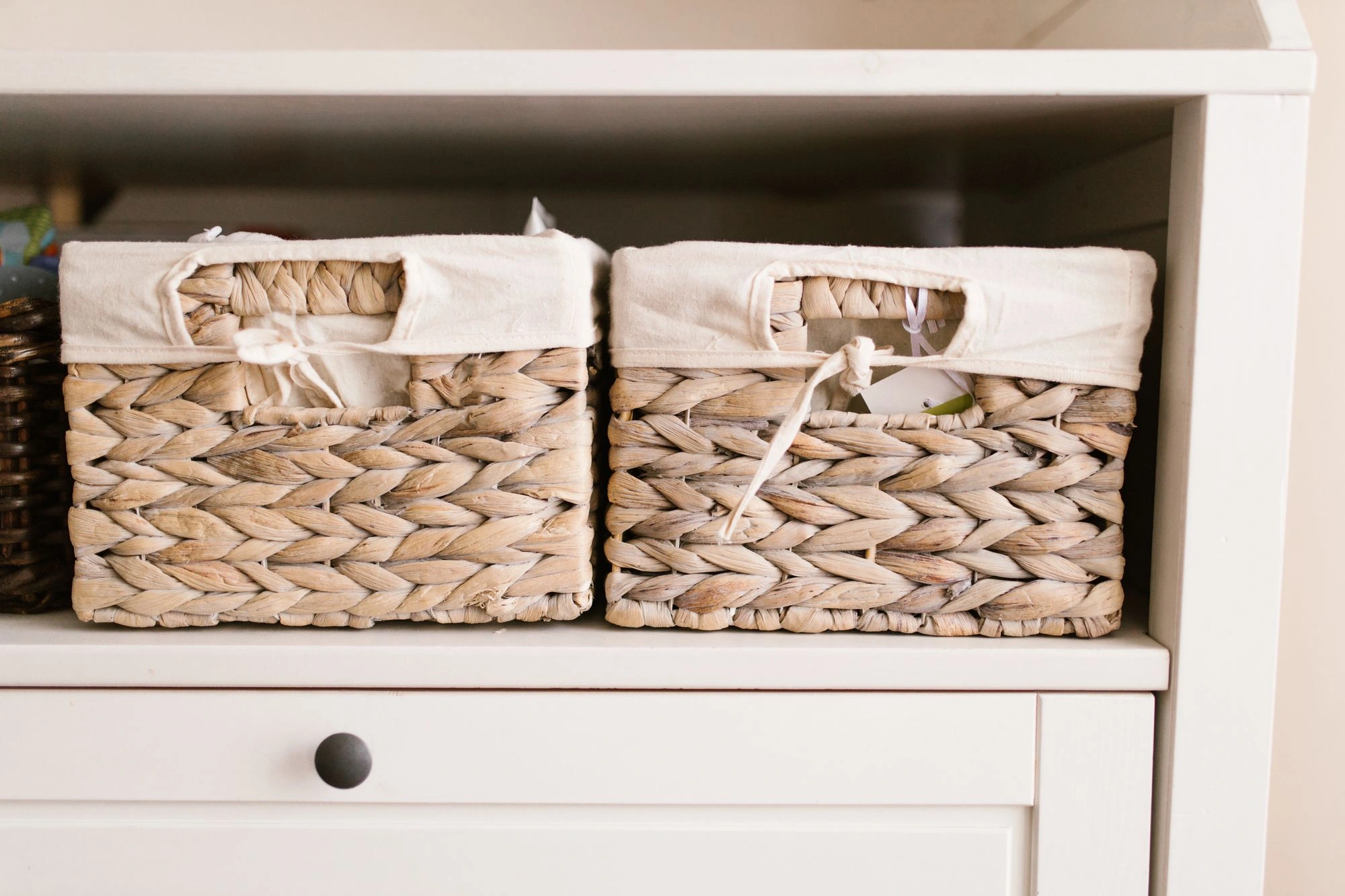 Two woven storage baskets arranged on a white shelf